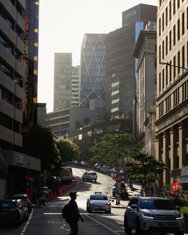 A person crossing an Auckland city street in early morning sunlight