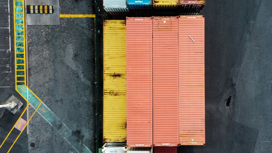 Aerial view of red and white shipping containers stacked at an Auckland port