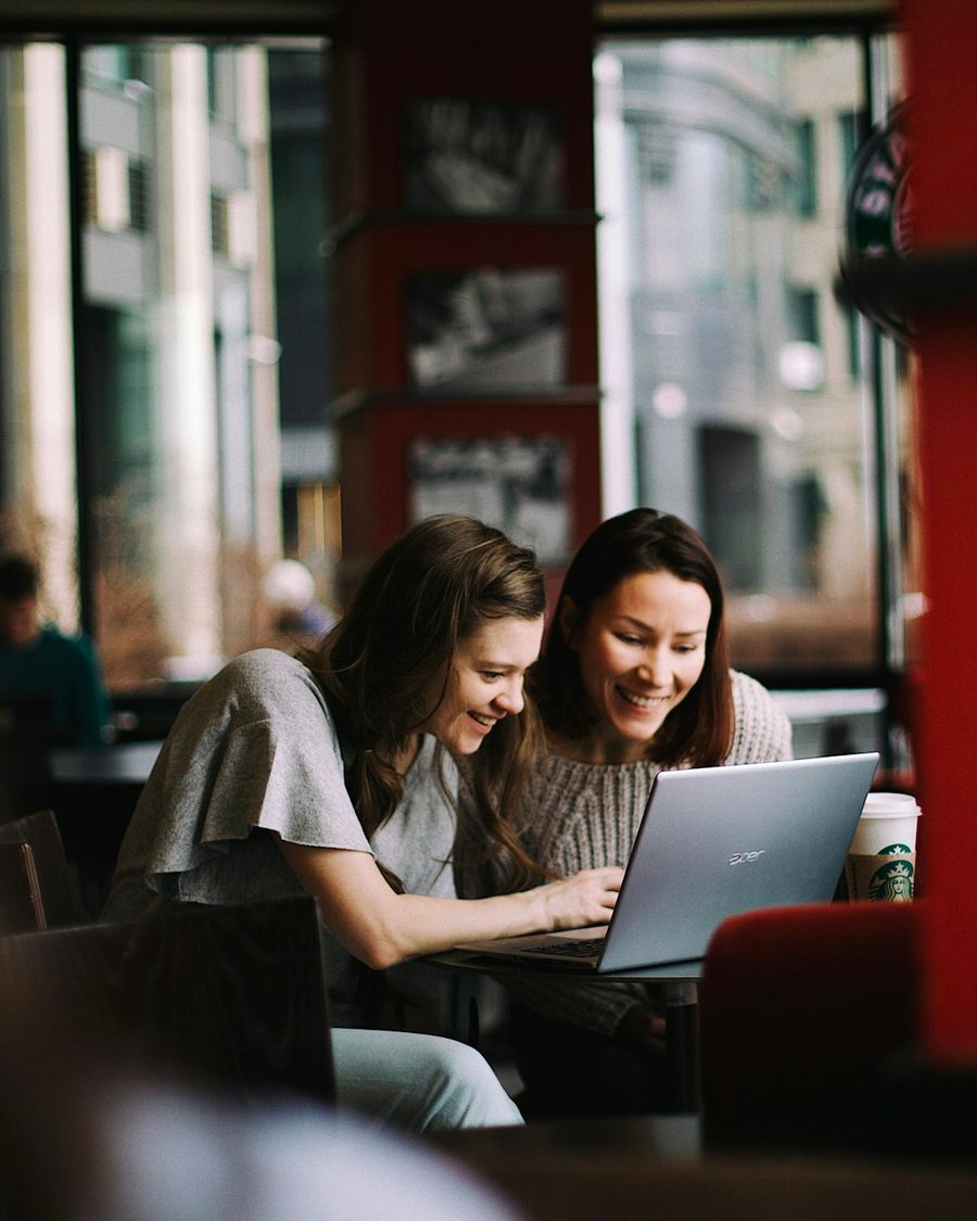 Two co-founders looking at a laptop screen together in a cafe