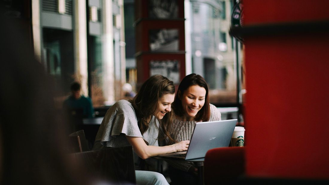 Two co-founders looking at a laptop screen together in a cafe