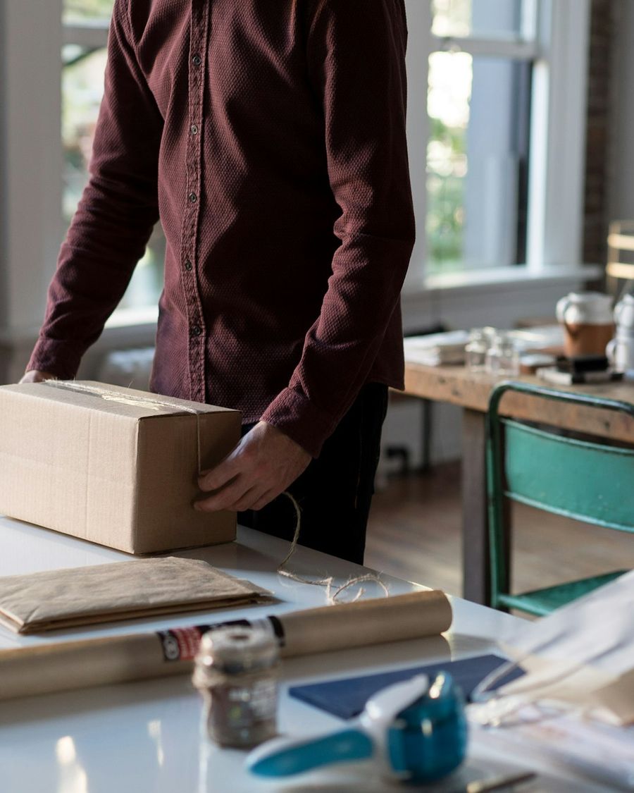 Hands holding a sealed cardboard box ready to ship from a small online business